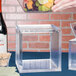 A person using an American Metalcraft square acrylic riser to display fruit.