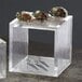 A clear acrylic square riser with oysters on it with a fork and knife.