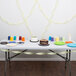 A table with a cake and cups on it with Creative Converting Mimosa Yellow streamers hanging above.