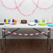 A table with a cake and pink streamers on it.