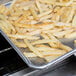 A Thunder Group wire-in-rim bun pan filled with french fries is being cooked.