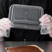 A person holding a clear plastic container with a Solut brownie pan inside.