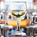 An Anchor Hocking Excellency wine glass filled with white wine on a table.