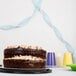 A blue cake with a pastel blue streamer decorated on a table.