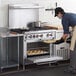 A man using a Cooking Performance Group liquid propane range to cook food in a professional kitchen.