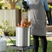 A woman using a Backyard Pro turkey fryer to cook a turkey.