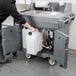 A person pushing a Cambro portable sink cart with a water container.