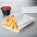 A Carnival King paper bag of french fries on a table with a cup of ketchup.