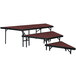 A National Public Seating stage pie unit with red carpet on stage tables.