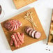 An American Metalcraft carbonized bamboo serving board with meat and toothpicks on it.