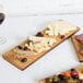 An American Metalcraft carbonized bamboo serving board with a group of cheese and olives.