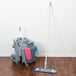 A Unger SmartColor floor mop and bucket on a wood floor.