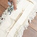 A person using a Carlisle dry dust mop pad to clean a white rug.