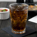 A glass of ice tea with ice on a table.
