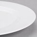 A close-up of a 10 Strawberry Street Classic White Porcelain Dinner Plate with a rim.