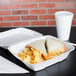 A sandwich and potato chips in a white styrofoam container.