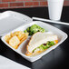A sandwich with lettuce and cheese in a white foam container.