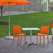 Grosfillex orange chairs on a stone patio.