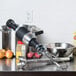 A KitchenAid immersion blender on a counter with a bowl of flour, a bottle, a potato, and a yellow onion.