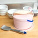 A bowl of ice cream with a Vollrath blue aluminum ice cream spade.