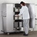 A woman putting food into a large metal cabinet.