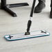 A person using a Lavex 18" microfiber mop to clean a floor.