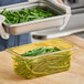 A person holding a Cambro plastic food pan filled with green beans.