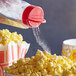 A hand pouring Carnival King Popcorn Salt onto a bowl of popcorn.
