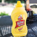 A yellow bottle of Woeber's Salad Style Mustard on a table.
