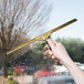 A hand using a Unger brass window squeegee on a window.