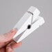 A hand holding an American Metalcraft white clothespin card holder.