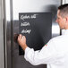 A man writing on an American Metalcraft chalkboard roll.