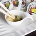 A plate of sushi with Arcoroc porcelain spoons on a table in an Asian cuisine restaurant.