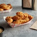 A red check paper food tray with fried chicken strips.