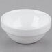 An Arcoroc white porcelain bowl on a gray surface.