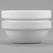 Two Arcoroc white porcelain stackable bowls sitting on a gray surface.