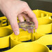 A hand holding a glass in a yellow Carlisle glass rack.