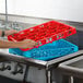 A person holding a red Carlisle glass rack extender over a sink.