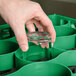 A hand holding a glass in a green Carlisle glass rack.