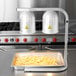 An Avantco countertop heat lamp with two bulbs over trays of french fries.