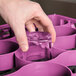 A hand reaching for a purple glass inside a lavender Carlisle glass rack.