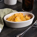 An ivory oval baker dish filled with food next to a glass of soda.