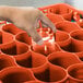 A hand holding a glass in an orange Carlisle glass rack.