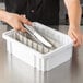 A person using a knife and tongs in a white Metro Divider Tote Box.