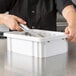 A person cutting food in a white Metro Divider Tote Box on a counter.