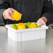 A person holding a Metro white tote container with lemons and limes.