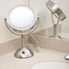 A Conair freestanding vanity mirror with a round LED light on a white counter.