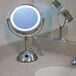 A Conair freestanding vanity mirror with a light on a white bathroom vanity.