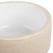 A beige stoneware ramekin with a white interior and rim.