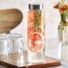 A Libbey glass water bottle with lemon and rosemary slices on a wooden counter.